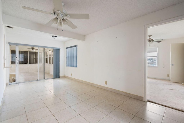 spare room with light tile patterned floors, visible vents, a ceiling fan, a textured ceiling, and baseboards