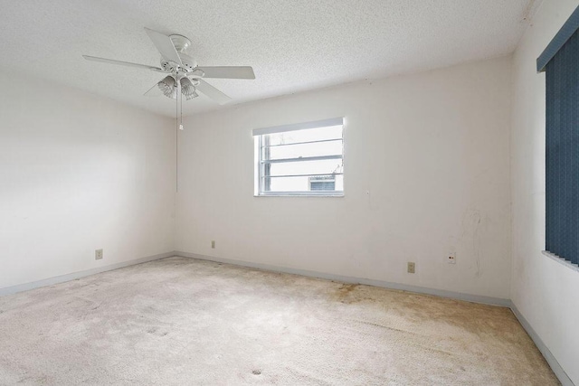 spare room featuring a textured ceiling, light carpet, a ceiling fan, and baseboards