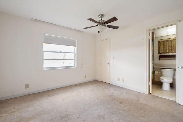 unfurnished bedroom with carpet floors, a ceiling fan, baseboards, and connected bathroom