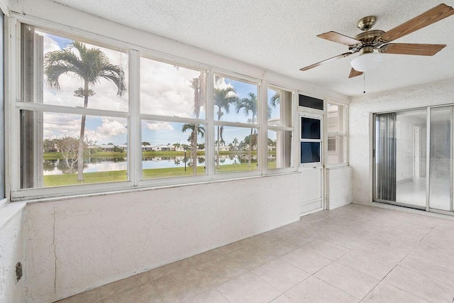 unfurnished sunroom featuring a water view, plenty of natural light, and ceiling fan