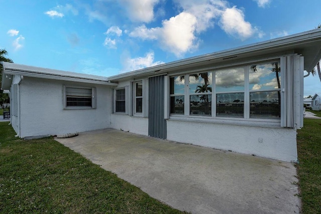 view of property exterior featuring a yard, a patio area, and stucco siding