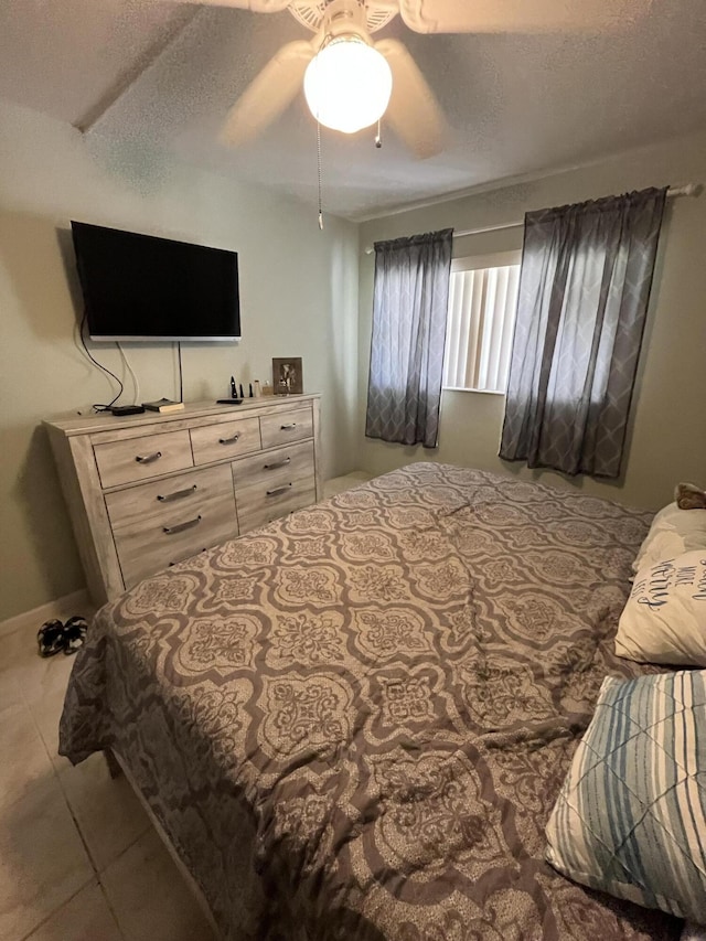 bedroom with a textured ceiling, baseboards, a ceiling fan, and tile patterned floors