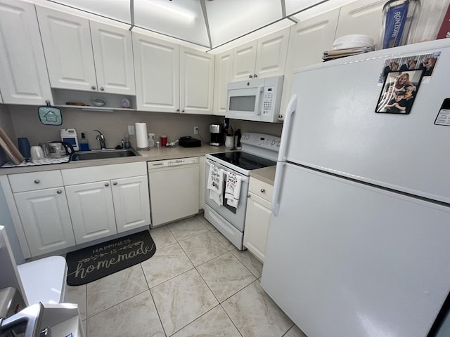 kitchen with light tile patterned floors, light countertops, white cabinetry, a sink, and white appliances