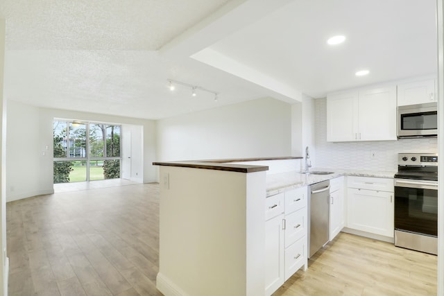 kitchen with a peninsula, appliances with stainless steel finishes, and open floor plan