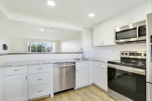 kitchen featuring stainless steel appliances, white cabinetry, a sink, and light stone countertops