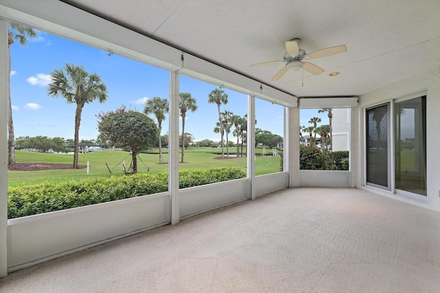 unfurnished sunroom featuring view of golf course and ceiling fan