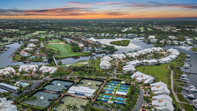 aerial view at dusk with a water view and a residential view