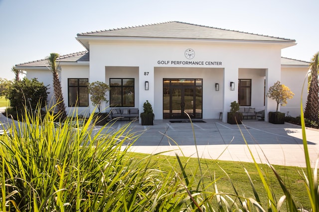 exterior space with stucco siding, a tiled roof, and a patio