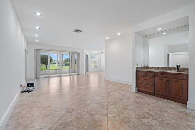 unfurnished living room featuring baseboards, visible vents, a sink, and recessed lighting