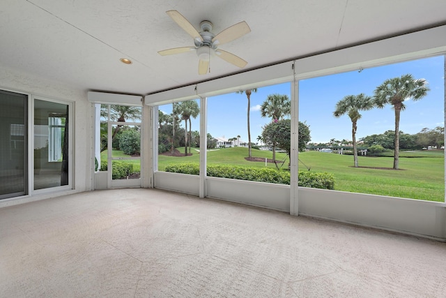 unfurnished sunroom with a ceiling fan and golf course view