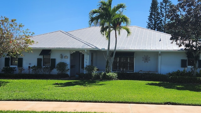 view of front of house featuring stucco siding, metal roof, and a front yard