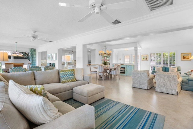 living area featuring ceiling fan with notable chandelier, ornamental molding, decorative columns, and visible vents