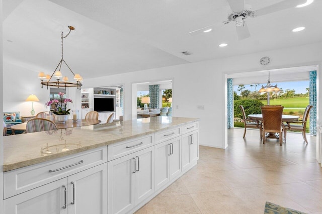 kitchen with hanging light fixtures, light stone countertops, white cabinets, and recessed lighting