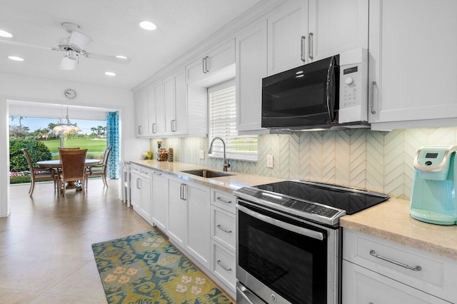 kitchen with stainless steel electric stove, decorative backsplash, white cabinets, a sink, and light stone countertops