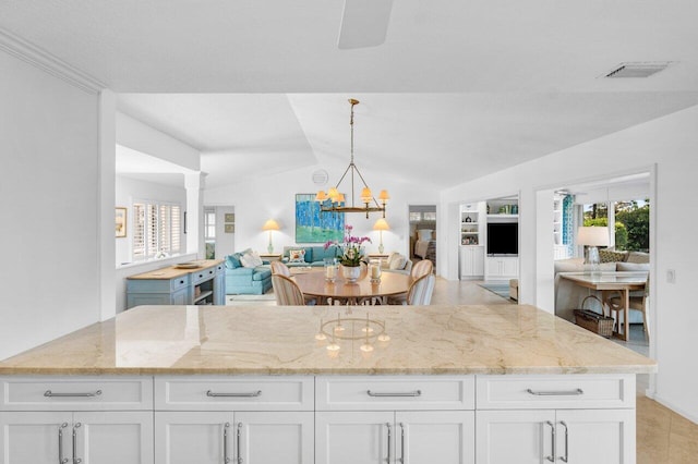 kitchen with open floor plan, white cabinets, visible vents, and light stone countertops