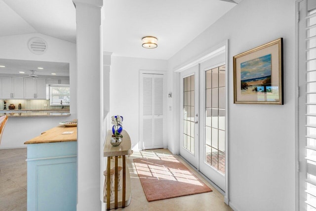 doorway to outside with ornate columns, light tile patterned floors, vaulted ceiling, and french doors