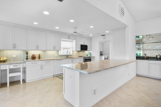 kitchen with black microwave, ceiling fan, separate washer and dryer, a sink, and white cabinetry