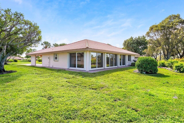 rear view of house with a lawn and a tile roof