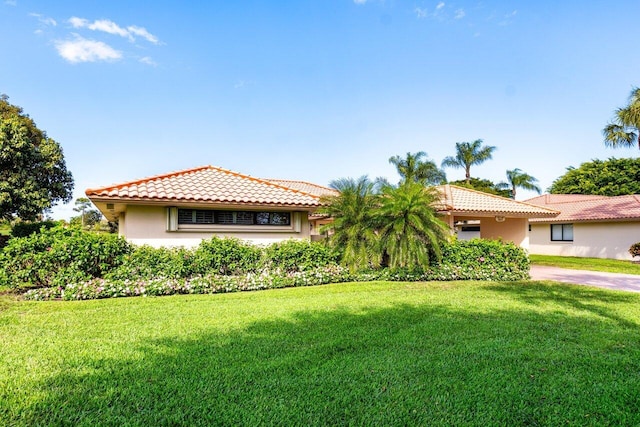 view of front of property featuring a tile roof, a front lawn, and stucco siding