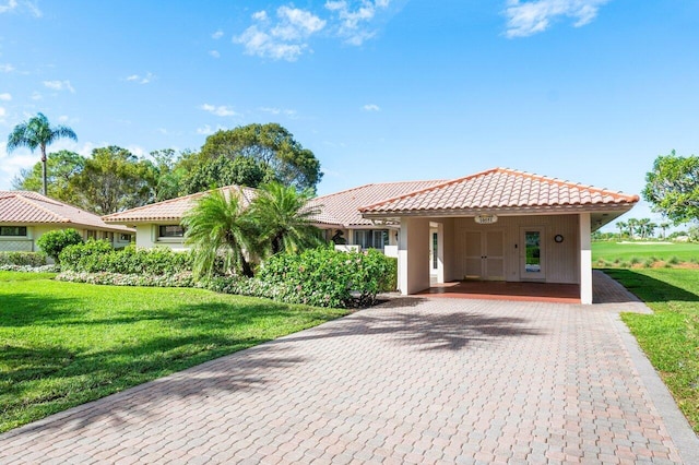 view of front of property featuring decorative driveway, a front yard, a tile roof, and stucco siding