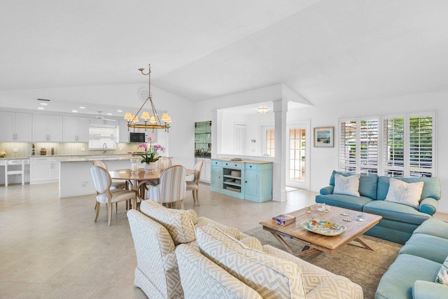 living area with vaulted ceiling, a chandelier, and decorative columns