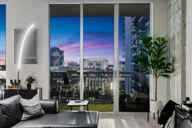 living area with floor to ceiling windows, a city view, and wood finished floors