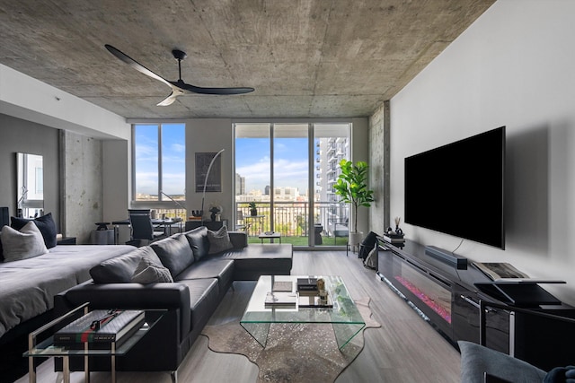 living room with wood finished floors, a ceiling fan, and floor to ceiling windows