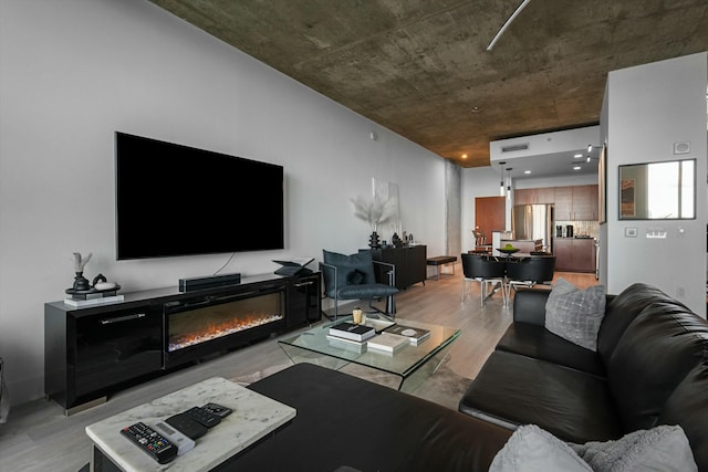 living area with light wood-style floors and a glass covered fireplace