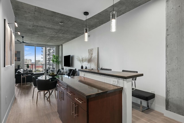 bar with light wood-type flooring, baseboards, a ceiling fan, and decorative light fixtures