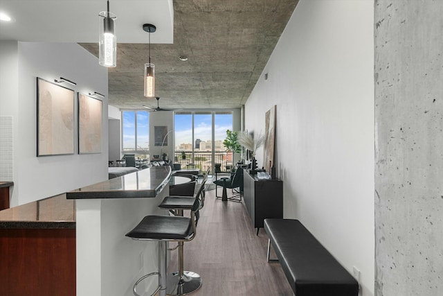 kitchen with dark countertops, hanging light fixtures, dark wood-type flooring, expansive windows, and a kitchen island