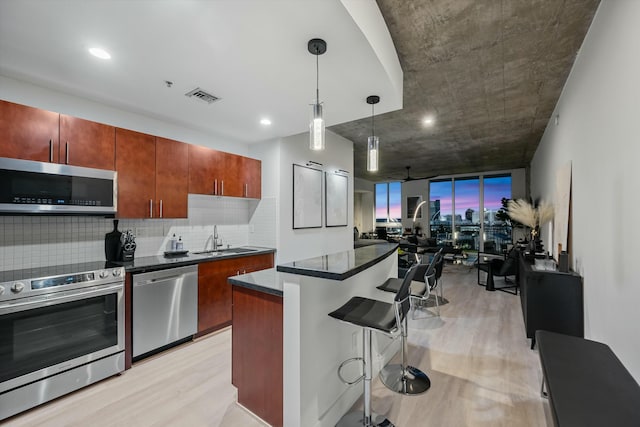 kitchen with visible vents, stainless steel appliances, a sink, and light wood-style flooring