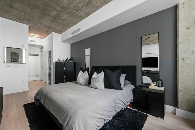 bedroom featuring visible vents, ensuite bath, baseboards, and wood finished floors