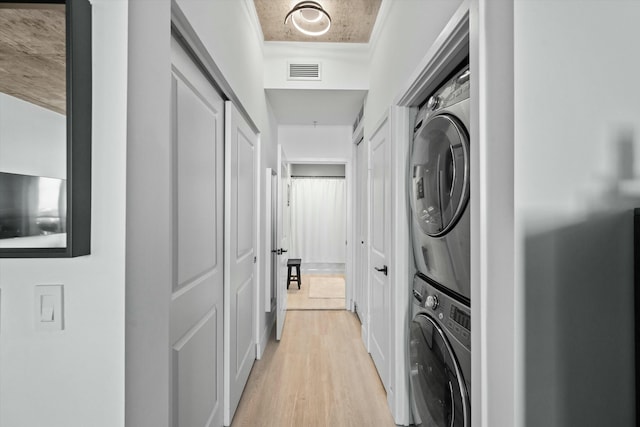 washroom featuring stacked washer and dryer, visible vents, and light wood-style floors