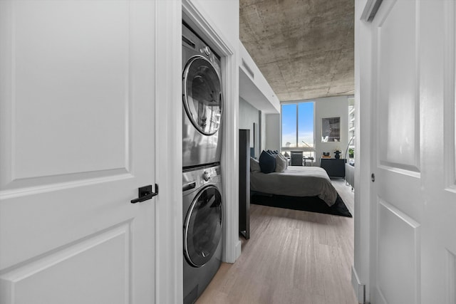 washroom featuring stacked washing maching and dryer, laundry area, and wood finished floors