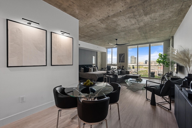 dining area featuring ceiling fan, wood finished floors, baseboards, floor to ceiling windows, and a view of city