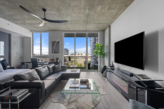 living area featuring a ceiling fan, expansive windows, and wood finished floors