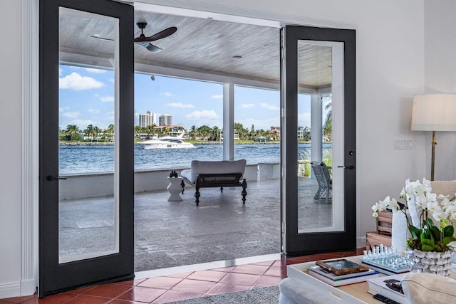 doorway to outside featuring tile patterned flooring, a water view, and ceiling fan