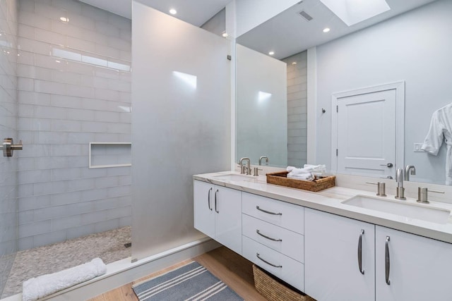 full bathroom featuring double vanity, a skylight, visible vents, and a sink