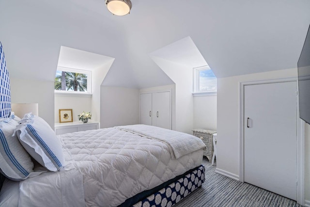 bedroom featuring multiple windows, dark carpet, and vaulted ceiling