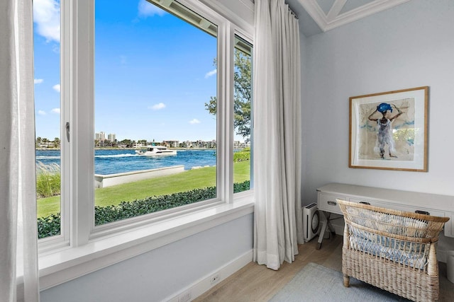 sitting room featuring ornamental molding, a water view, light wood-style flooring, and baseboards