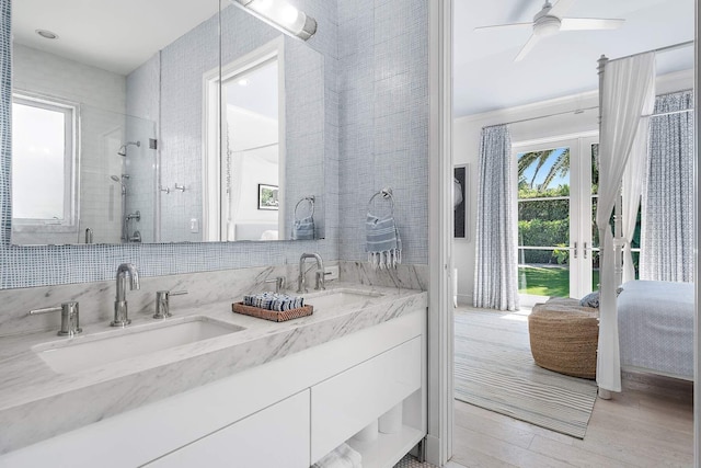 full bath featuring double vanity, connected bathroom, a sink, and wood finished floors