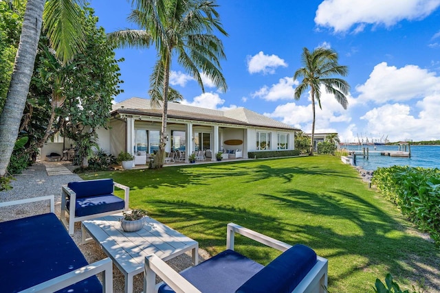 rear view of property with a patio area, a yard, and a water view