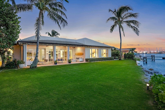 back of house with a patio and a lawn