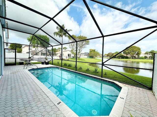 outdoor pool with a patio area, a yard, a water view, and a lanai