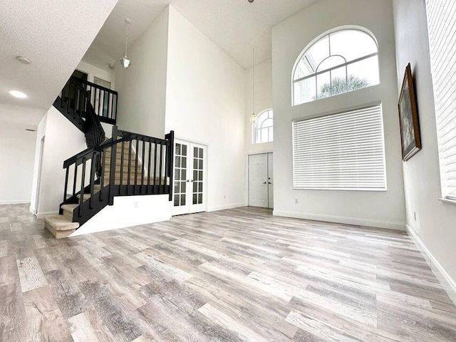 foyer featuring light wood-type flooring, baseboards, stairway, and french doors