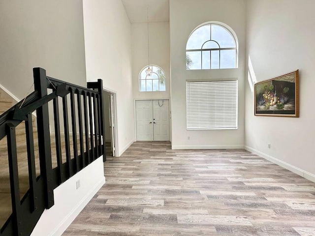 foyer featuring light wood-style floors, a high ceiling, and baseboards