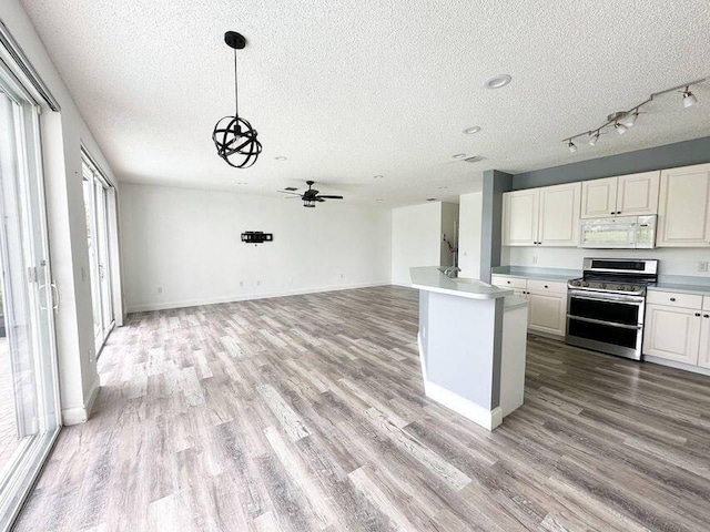 kitchen with range with two ovens, white microwave, white cabinetry, open floor plan, and light countertops