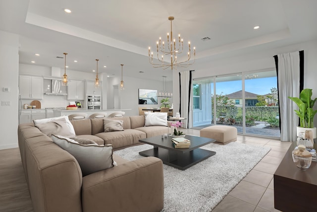 living area with a tray ceiling, recessed lighting, light tile patterned flooring, and an inviting chandelier