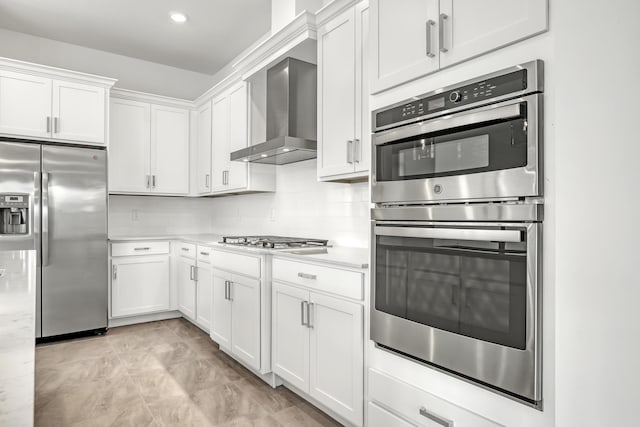 kitchen featuring light countertops, appliances with stainless steel finishes, wall chimney range hood, and white cabinets