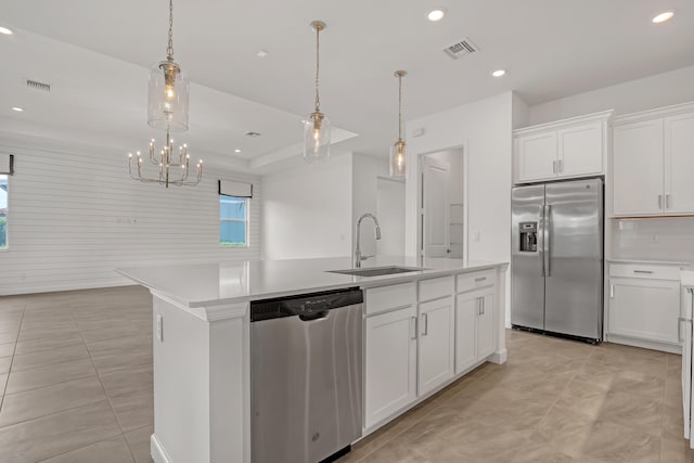 kitchen featuring light countertops, appliances with stainless steel finishes, a kitchen island with sink, and white cabinetry